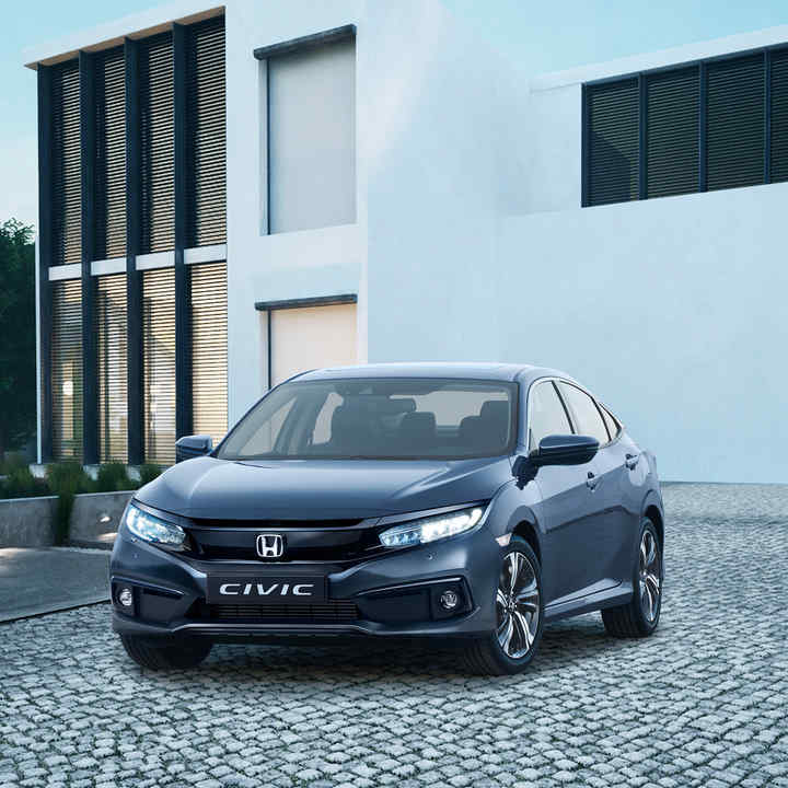 Driekwart vooraanzicht Honda Civic 4-deurs voor gebouw.