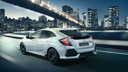 Driekwart achteraanzicht Honda Civic Black Edition, rijdend door de stad.