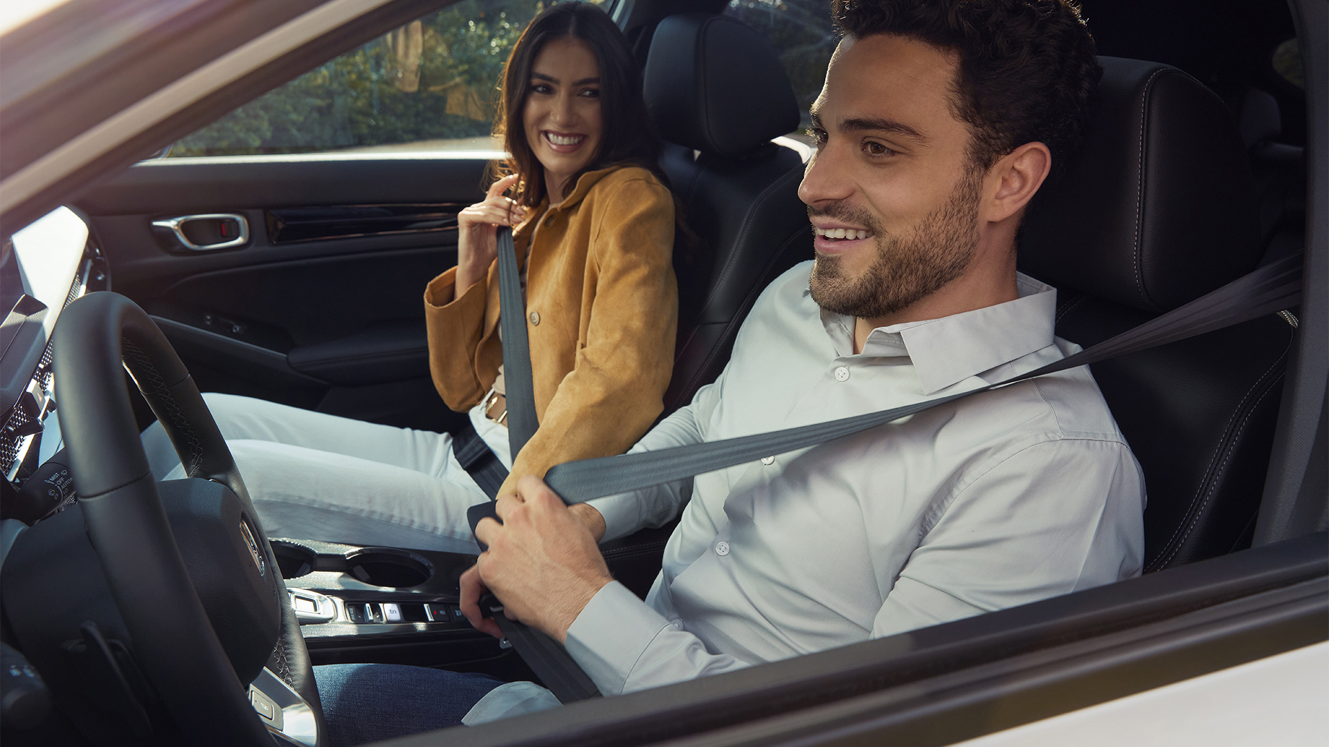 Two people fastening their seatbelts inside the Honda Civic Hybrid.