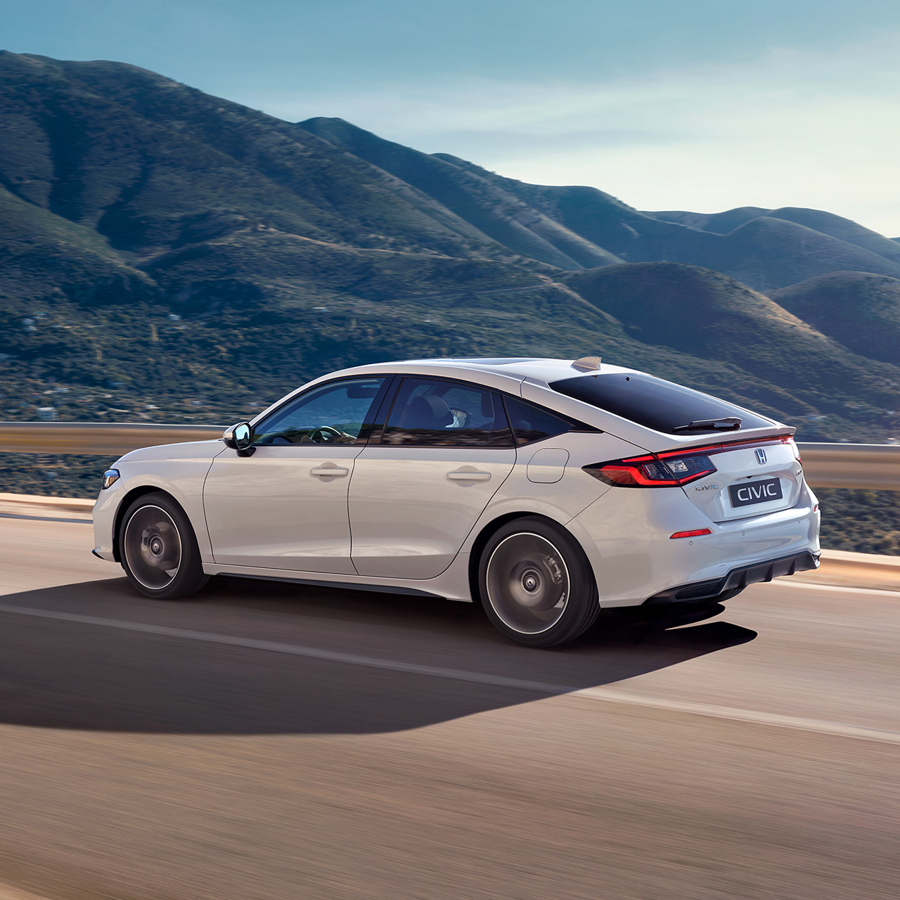 Honda Civic Hybrid in beweging op een snelweg, in een schilderachtig landschap.