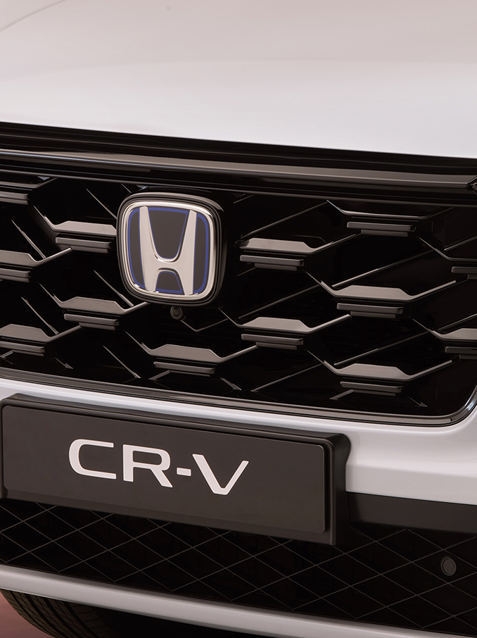 Close-up van de Honda CR-V-voorgrille, met een zwart honingraatpatroon, het Honda-logo centraal en de modelnaam CR-V eronder.