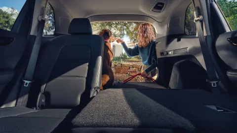 CR-V Hybrid SUV Achterzetels ingeklapt met vrouw en hond bij de open kofferbak. 