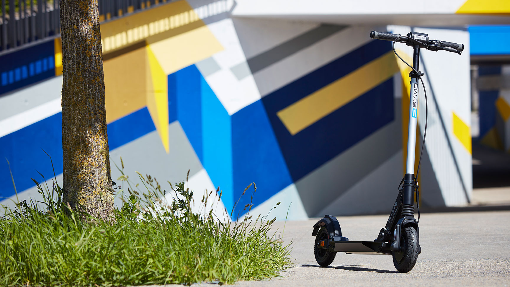 Honda eSYMO naast een boom en voor een fel gekleurde muur