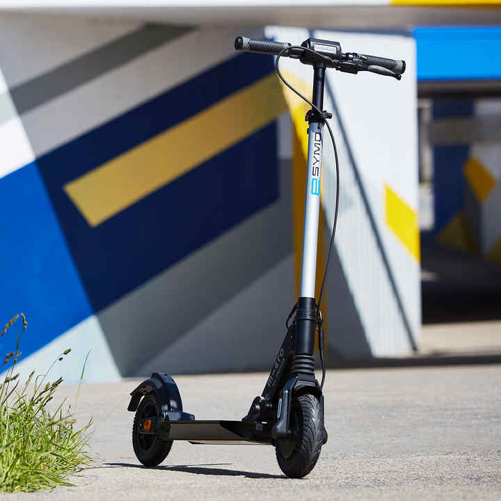 Honda eSYMO naast een boom en voor een fel gekleurde muur