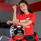 Dame die een rood Honda topje draagt, leunend op een Honda motorhelm.