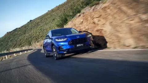 Honda ZR-V Hybrid Suv rijdt op de weg in een bergachtige omgeving.