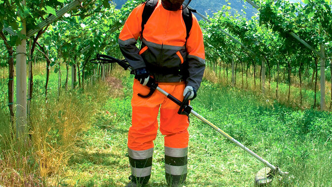 Model met ruggedragen bosmaaier van Honda op locatie in het veld.