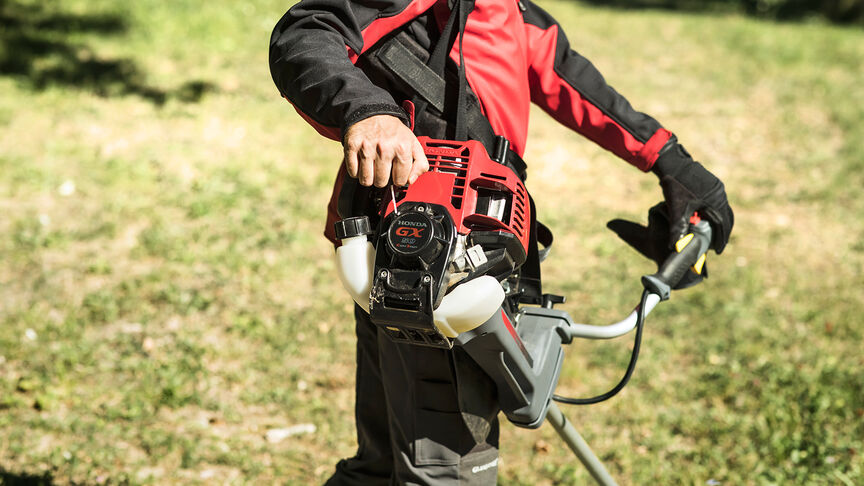 Model met ruggedragen bosmaaier op boslocatie.