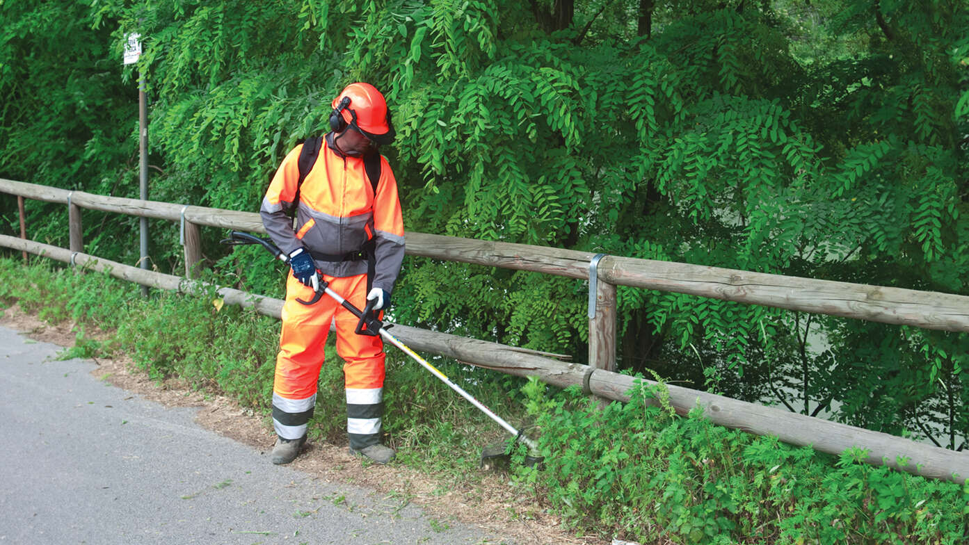 Model gebruikt de ruggedragen bosmaaier in parklocatie.