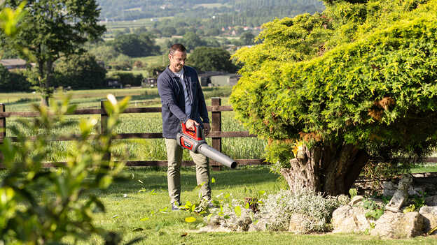 Man met accu bladblazer in de tuin