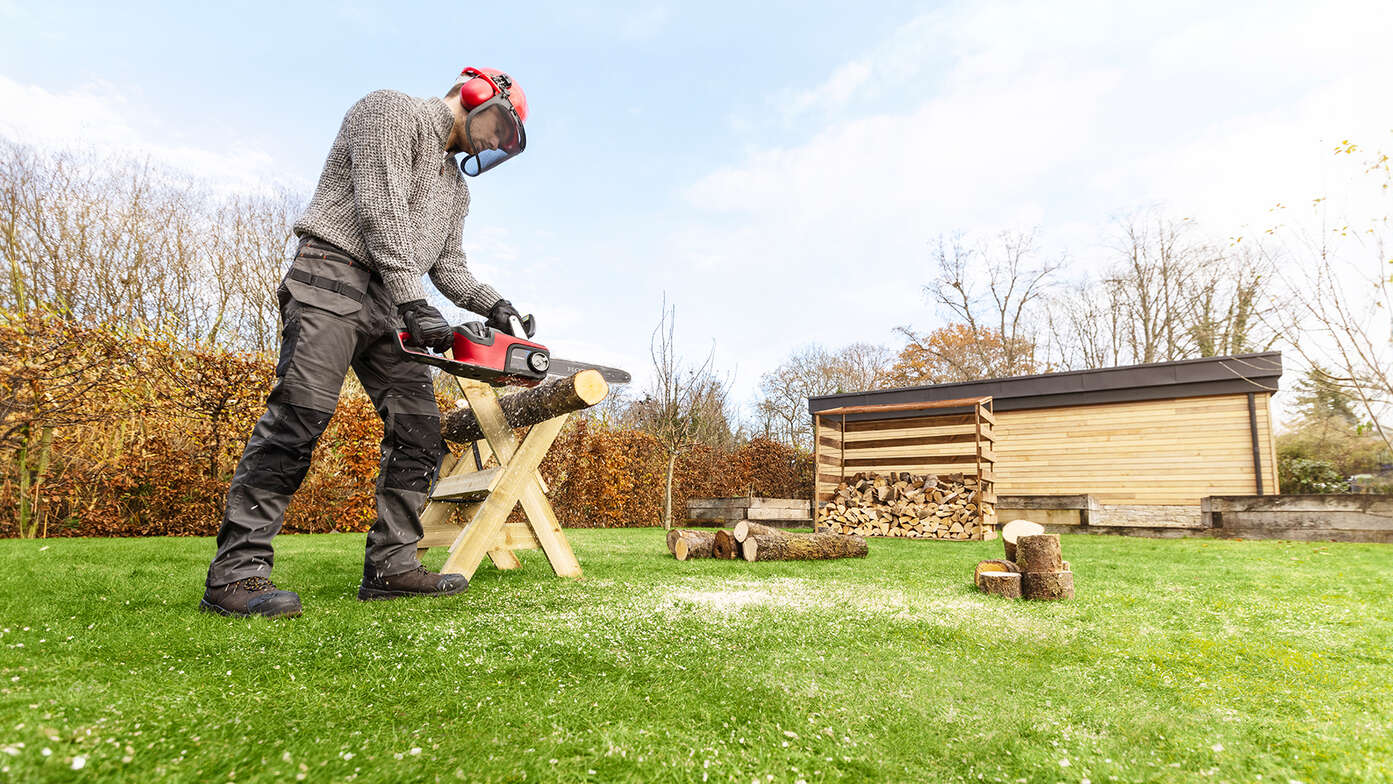 Man in een tuin aan de slag met een accu kettingzaag.