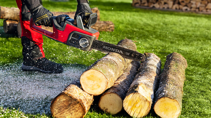 Close up van een model dat hout aan het zagen is met een snoerloze kettingzaag.