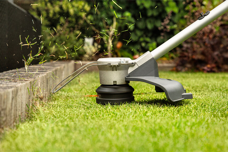 Accu grastrimmer demonstreert hoogwaardige snijlijn op gazon.