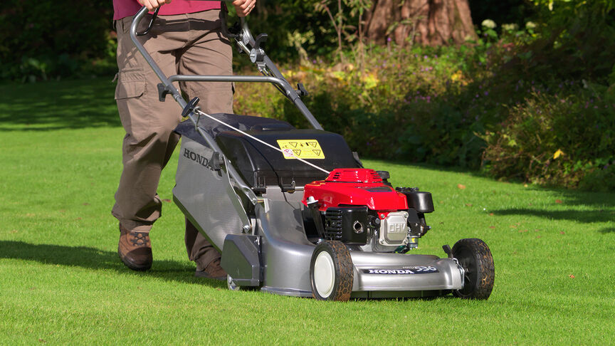 Man in tuinlocatie die gras maait met een Honda HRD grasmaaier.