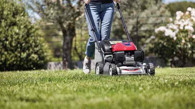 Honda IZY grasmaaier zijaanzicht met vrouw in tuinomgeving