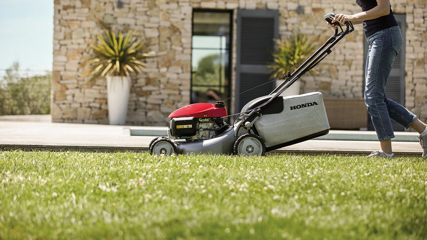 Honda IZY grasmaaier zijaanzicht met vrouw in tuin