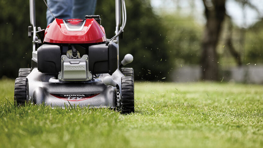 Honda IZY grasmaaier zijaanzicht met vrouw in tuin