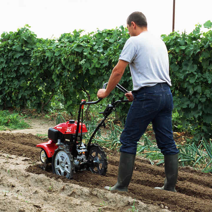 Man duwt roterende frees in veld