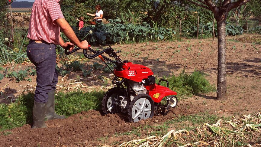 Vooraanzicht roterende tuinfrees aan het werk op het land.