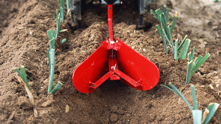 Vooraanzicht roterende tuinfrees aan het werk op het land.