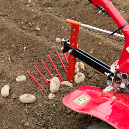 Tweewielige trekker met aardappelrooihulpstuk, tuinlocatie.