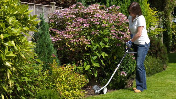 Honda Versatool met kantensnijderopzetstuk, in gebruik door model, tuinlocatie.