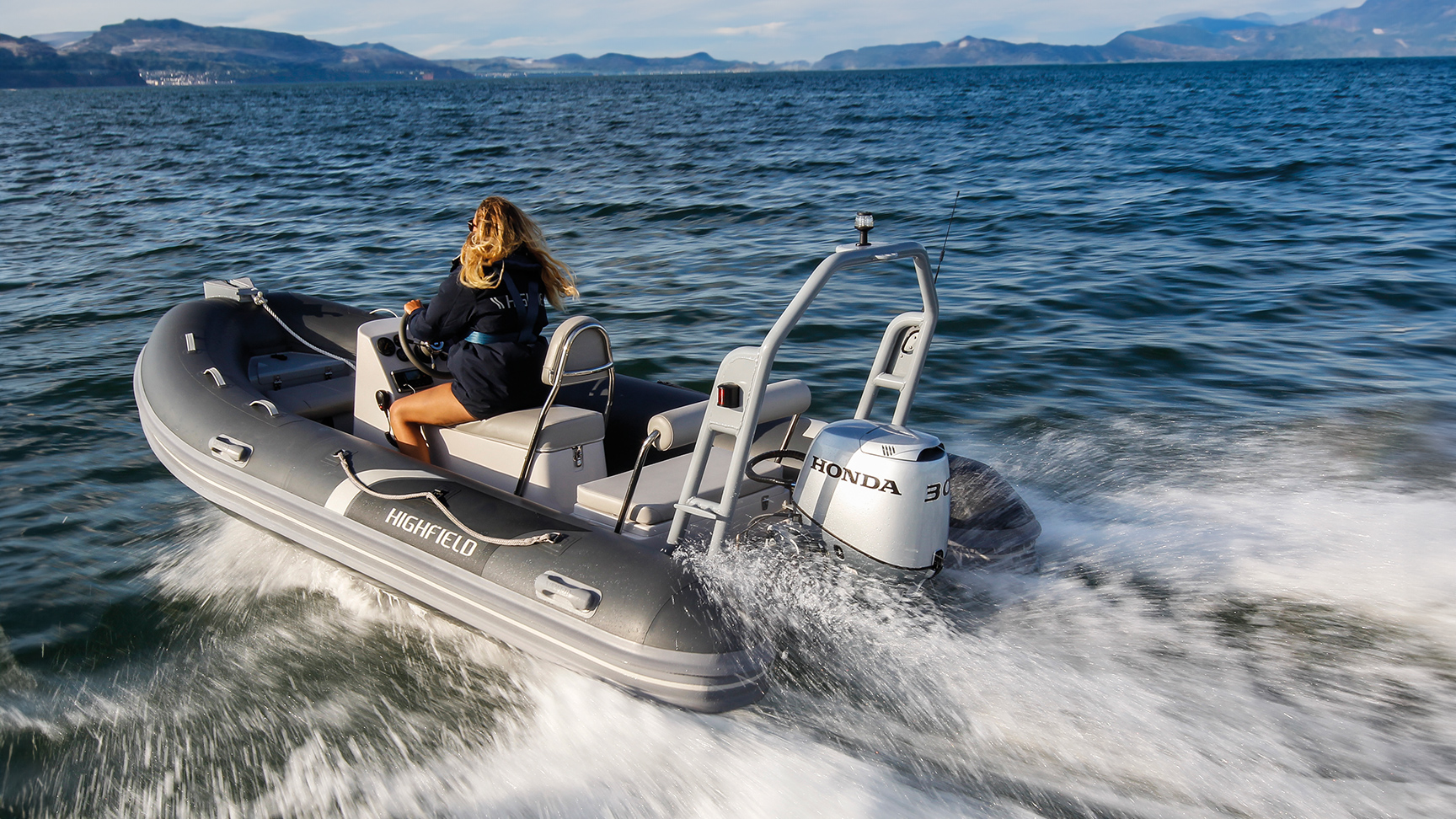 Dame op een Highfield-boot met een Honda BF30-motor op de oceaan.