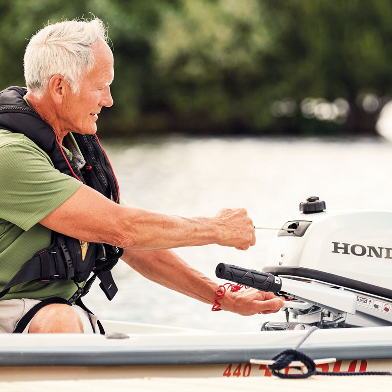 Man op een boot die een Honda BF5 motor start.