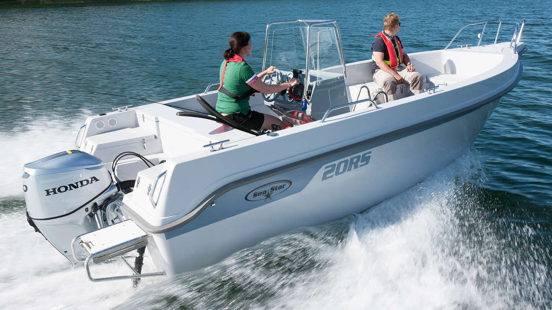 Boat using Honda engine, being used by models, coastal location.