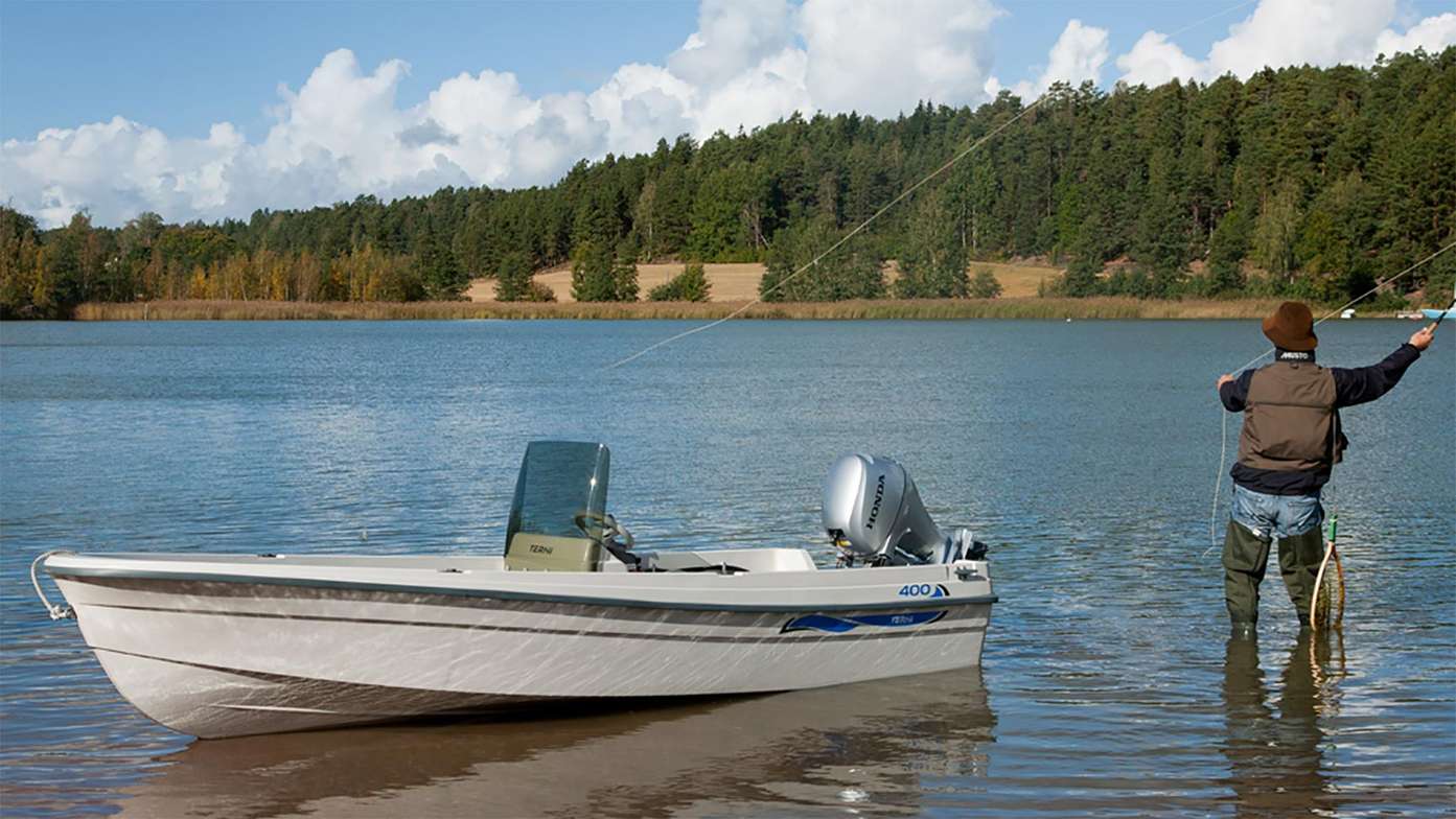 Man fishing beside a small boat with a Honda outboard engine