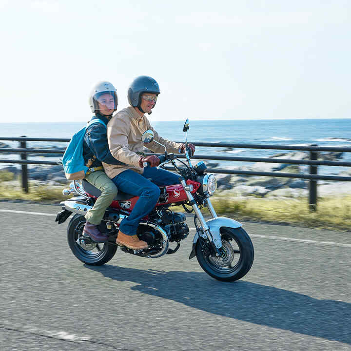 Honda Dax 125 op de kustweg met rijder en passagier