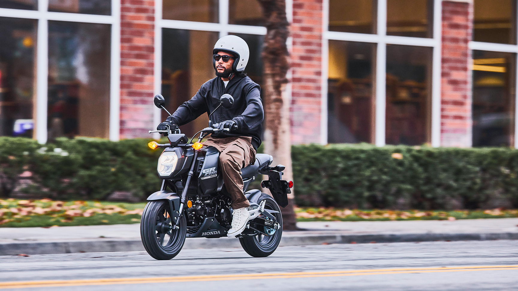 MSX125 Grom in het zwart geparkeerd met rijders die tegen elkaar spreken