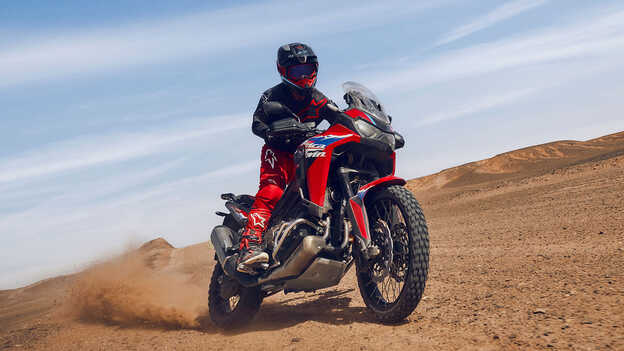 Model op de CRF1100L Africa Twin op locatie in de woestijn.