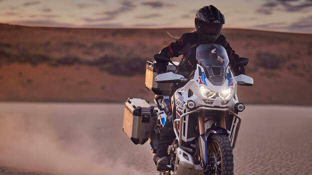 Rijder op Honda CRF1100 Africa Twin Adventure Sports in woestijnomgeving.