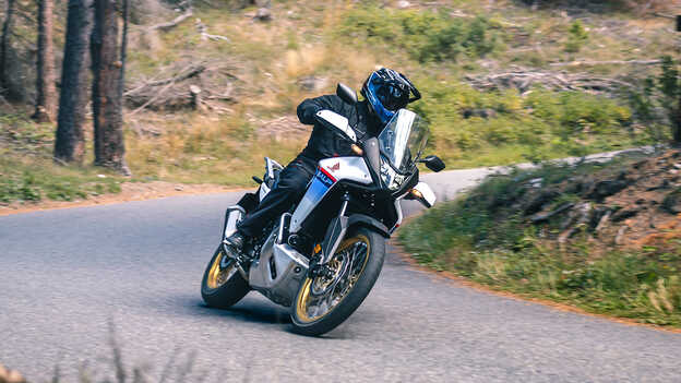 XL750 Transalp in de bocht van een bosrijke omgeving.