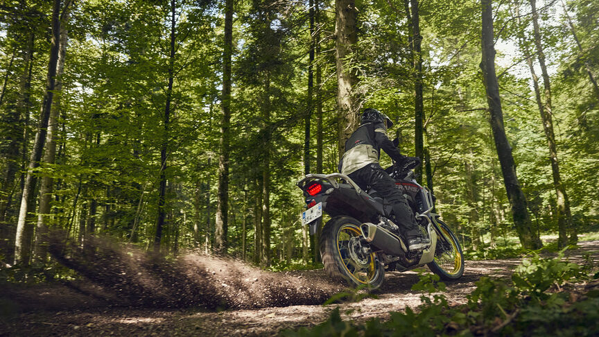 Model rijdend op XL750 Transalp in een bosomgeving.