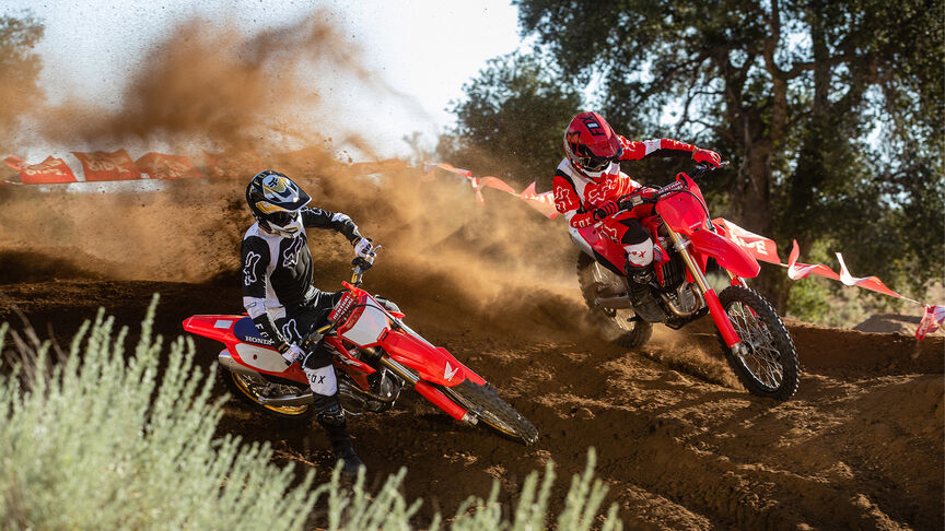 Twee rijders die over schansen springen op de Honda CRF450R.