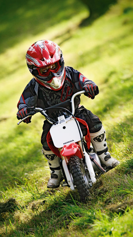 Vooraanzicht van CRF50F, met berijder op grashelling.