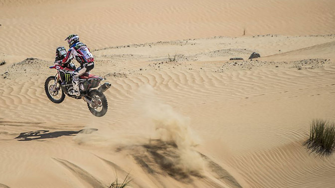 Driekwart achteraanzicht van Honda CRF450 rijdend door zand en duinen.