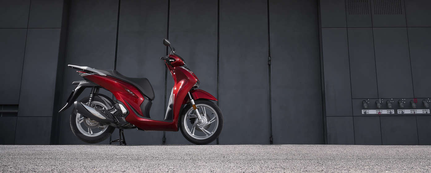 Honda SH125i geparkeerd in een stedelijke omgeving.