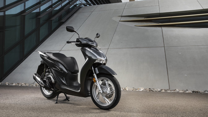 Honda Sh125i met topkoffer en windscherm in een straat.