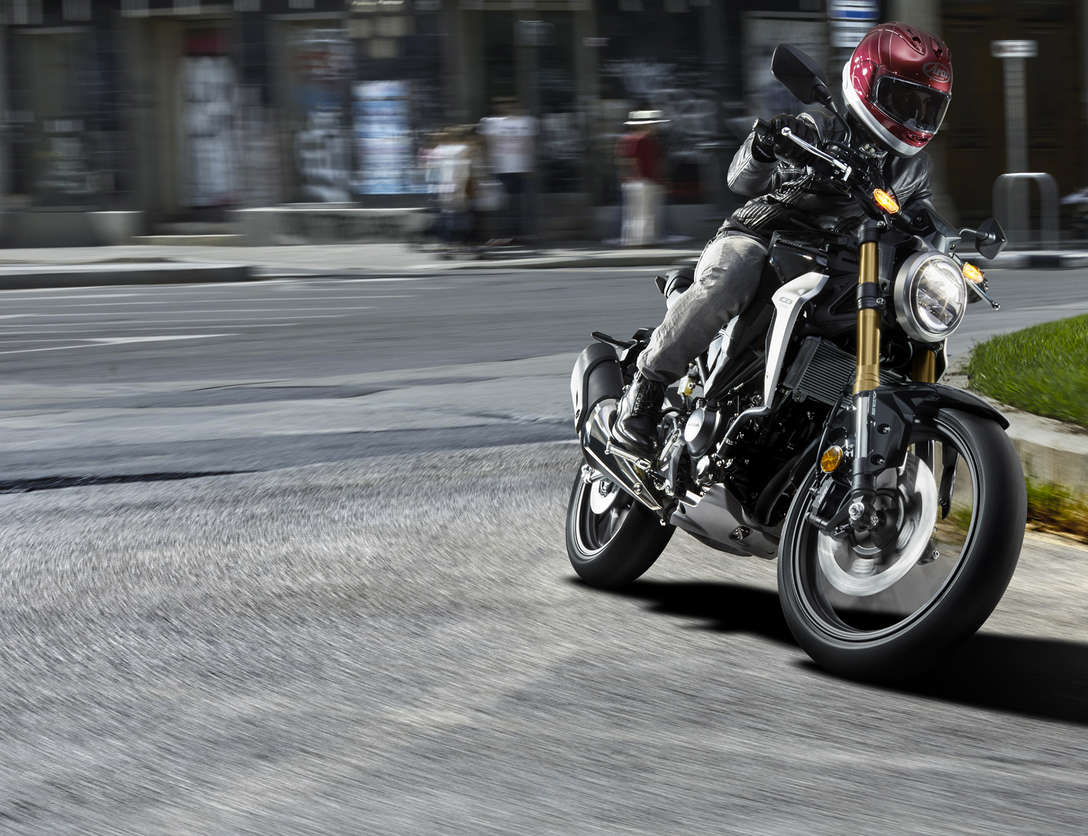Driekwart vooraanzicht Honda CB300R Neo Sports Café, rijdend op de weg.