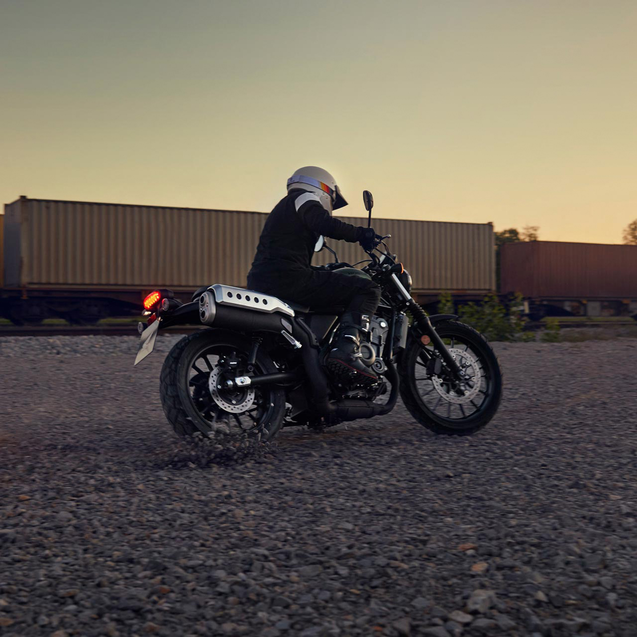 Model rijdend op de Honda CL500 motorfiets in een loods.