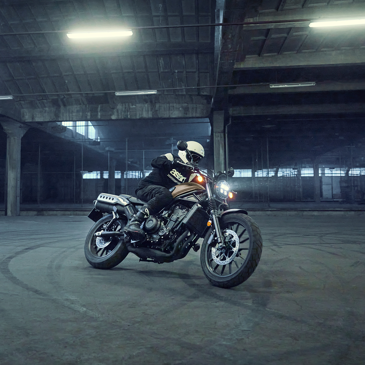 Model rijdend op de Honda CL500 motorfiets op een parkeerplaats.