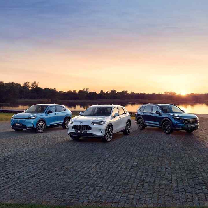 Honda e:Ny1, ZR-V, and CR-V in front of a sunset.